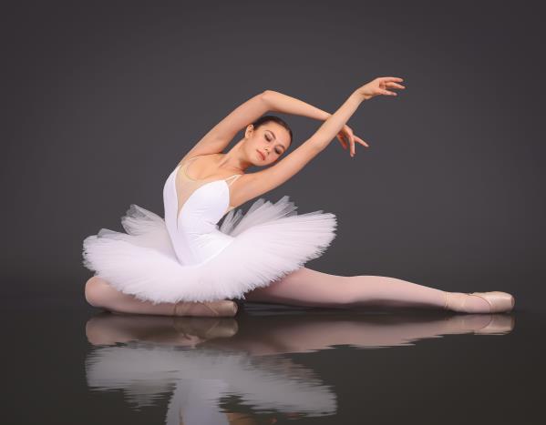 Classical ballerina in a white tutu performing a full split pose
